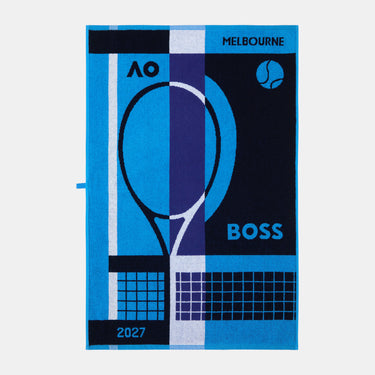A rectangular woven towel featuring a tennis-themed graphic design with the text 'MELBOURNE', 'AO', and 'BOSS', along with '2027'. The design uses vibrant blue, dark navy, and purple with white accents, and includes a stylized tennis racket and ball motifs.