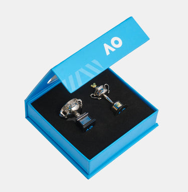 Two miniature silver trophy pendants with blue and gold accents are displayed inside an open bright blue presentation box with a black velvet lining. The brand logo 'AO' is visible on the inner lid and the base of the trophies.