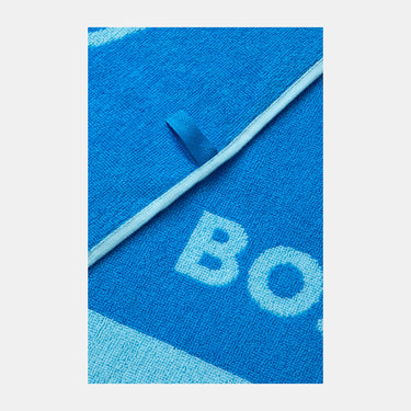 Close-up of a bright blue knit textile with a diagonal white stripe, a small blue tab, and large white letters 'BO' knitted into the fabric.