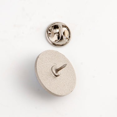 Backside of the lapel in the shape of a tennis ball, together with the lid of the lapel on a white background. 