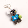 A plush koala keyring wearing a tennis hat and holding a tennis ball, with a blue badge displaying AO logo in white color.